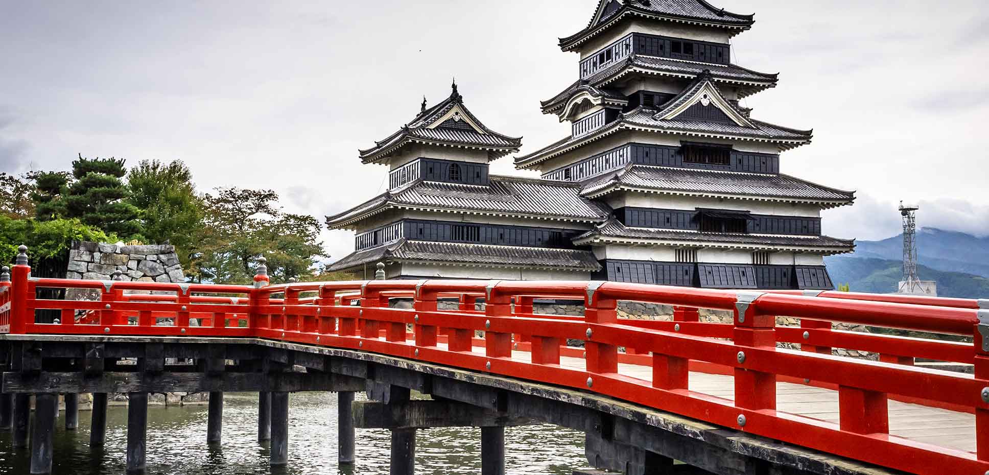 Red-railed bridge crossing river in front of Castle Nagano