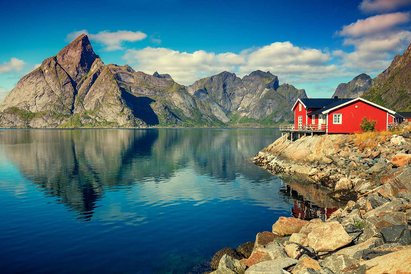 Mountains reflected on a lake with a red house on the shore