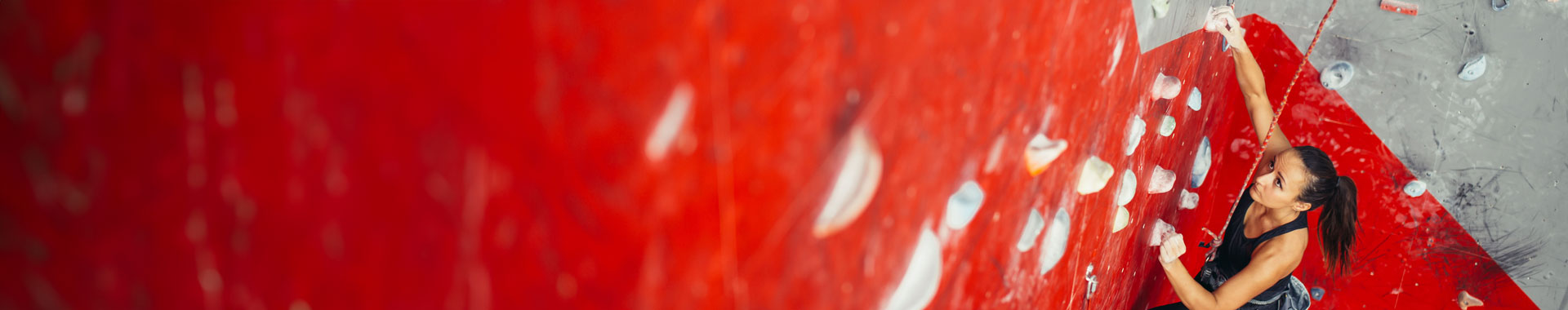 An exercising woman climbs a bold red rockwall