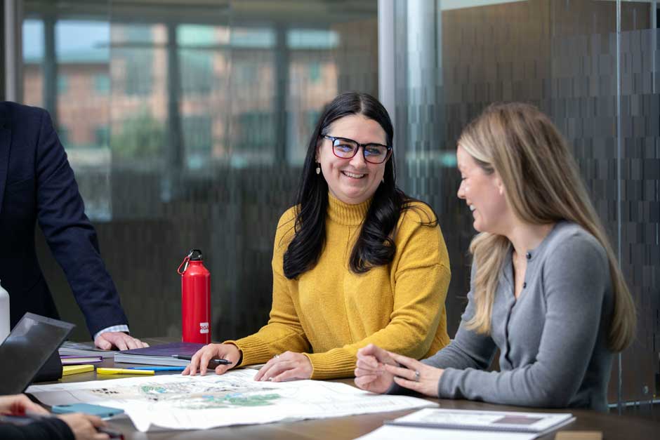 An engaged pair of women real estate professionals discuss opportunities.