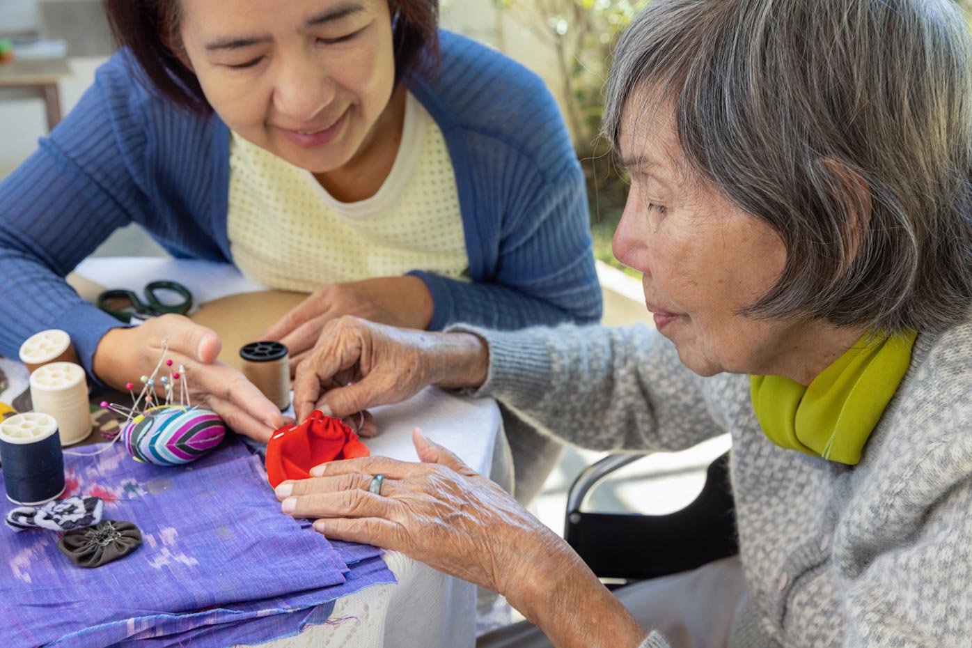 Elderly Asian woman with daughter sewing