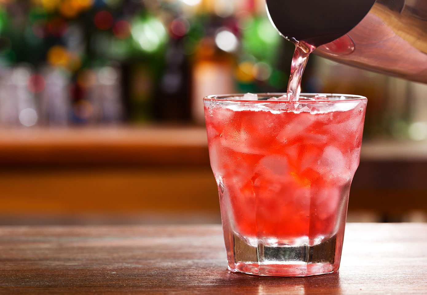 Red cocktail in rocks glass on a bar