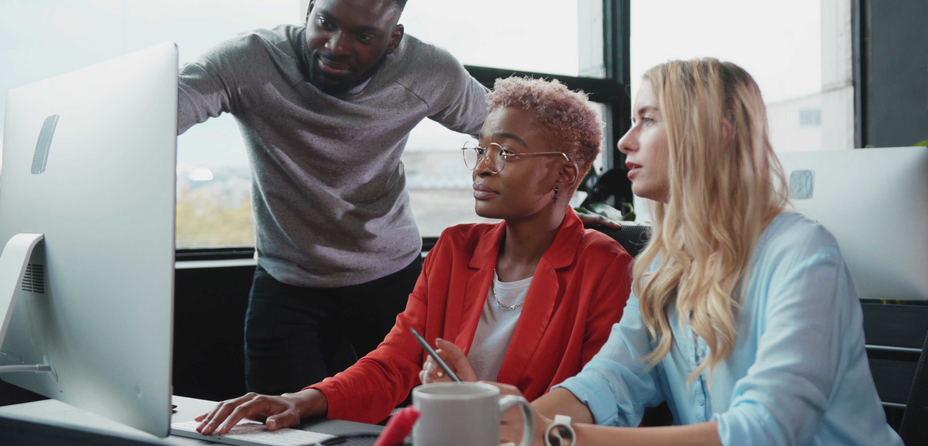 A cluster of actuaries gather around a computer to discuss data analysis