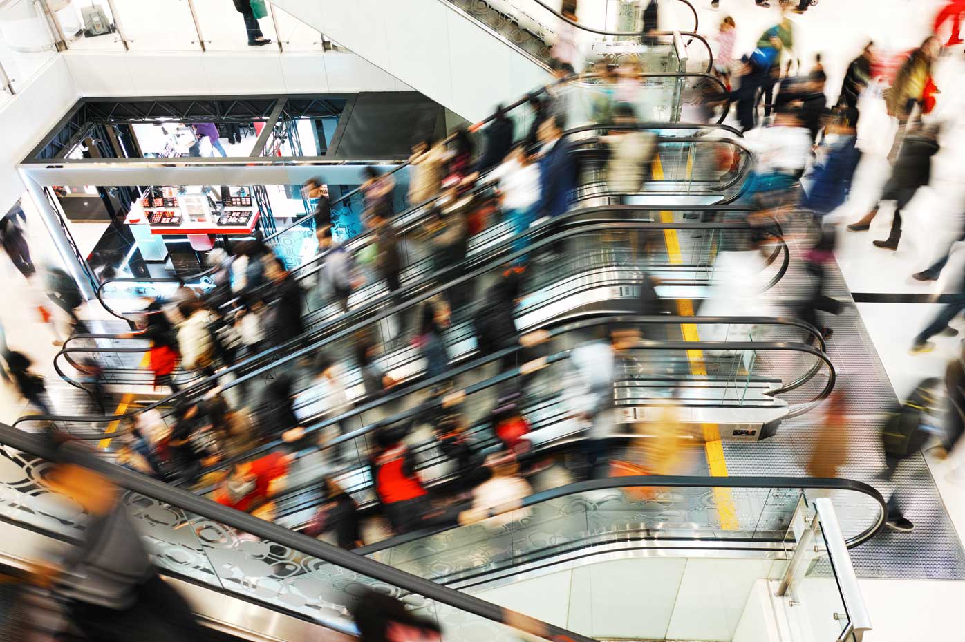 Image of shoppers moving in a mall escalator