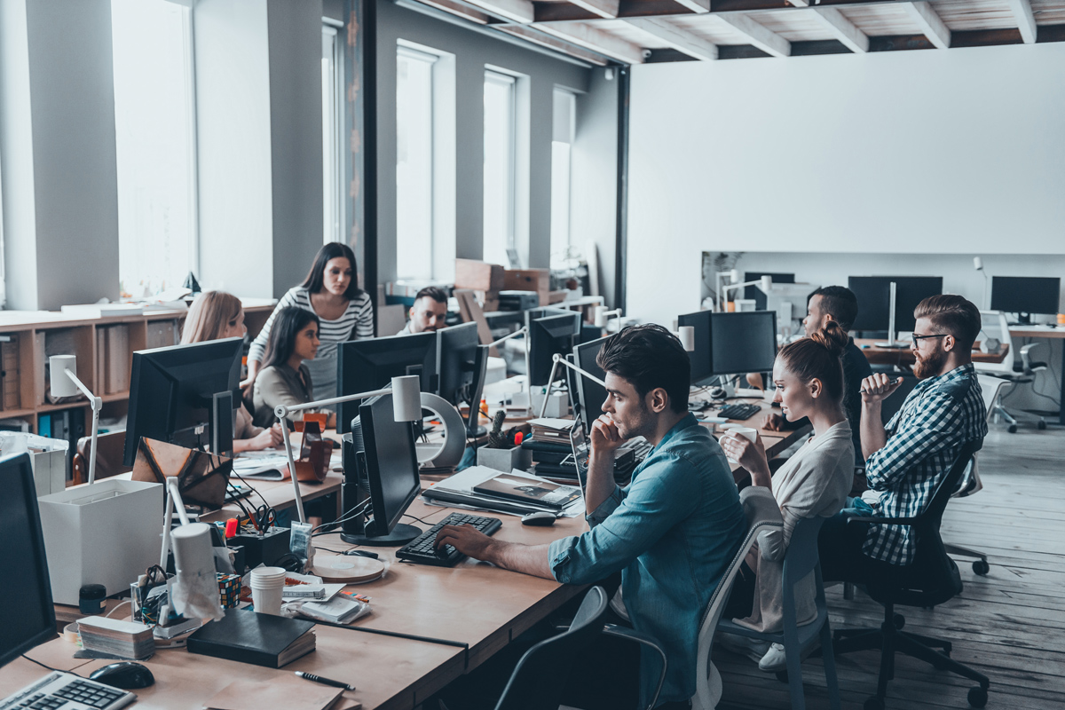 Image of a team gathered around computers in an open plan office