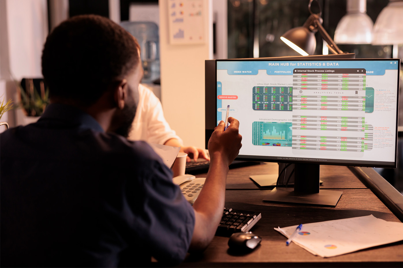 African American man points at a computer screen displaying analytics and data