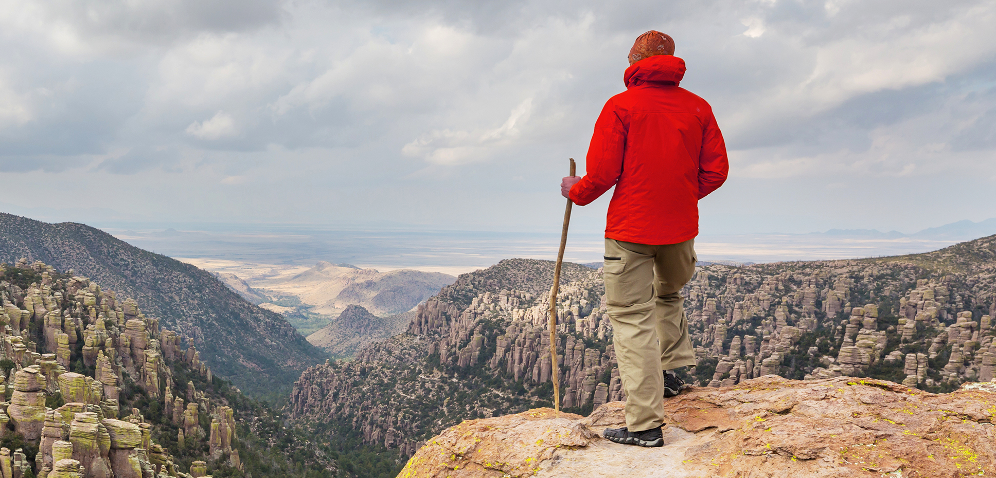 Hiker in red jacket looking over cliff