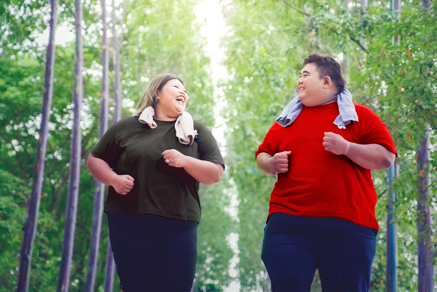 Two larger people - a woman and man - exercise outdoors on a forest path