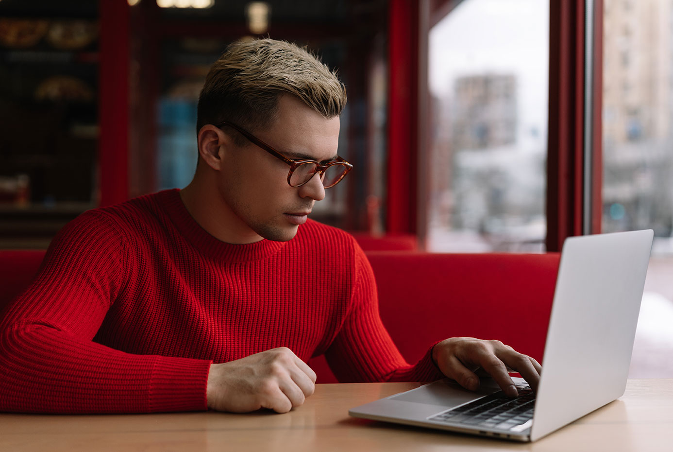 Man in red sweater looking at laptop