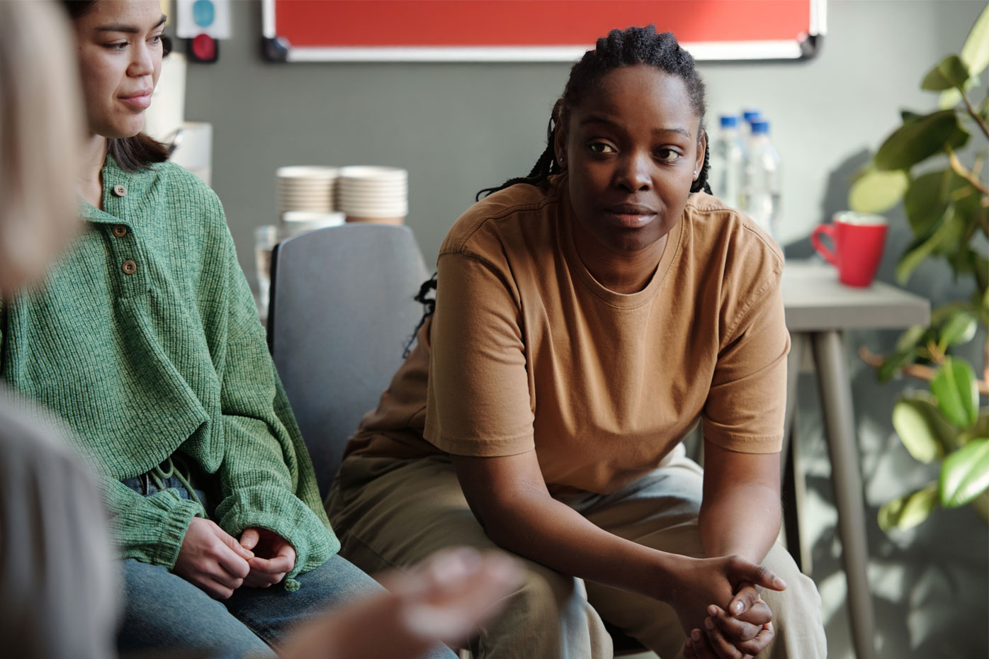 An African American woman leans forward in her chair during a group therapy session