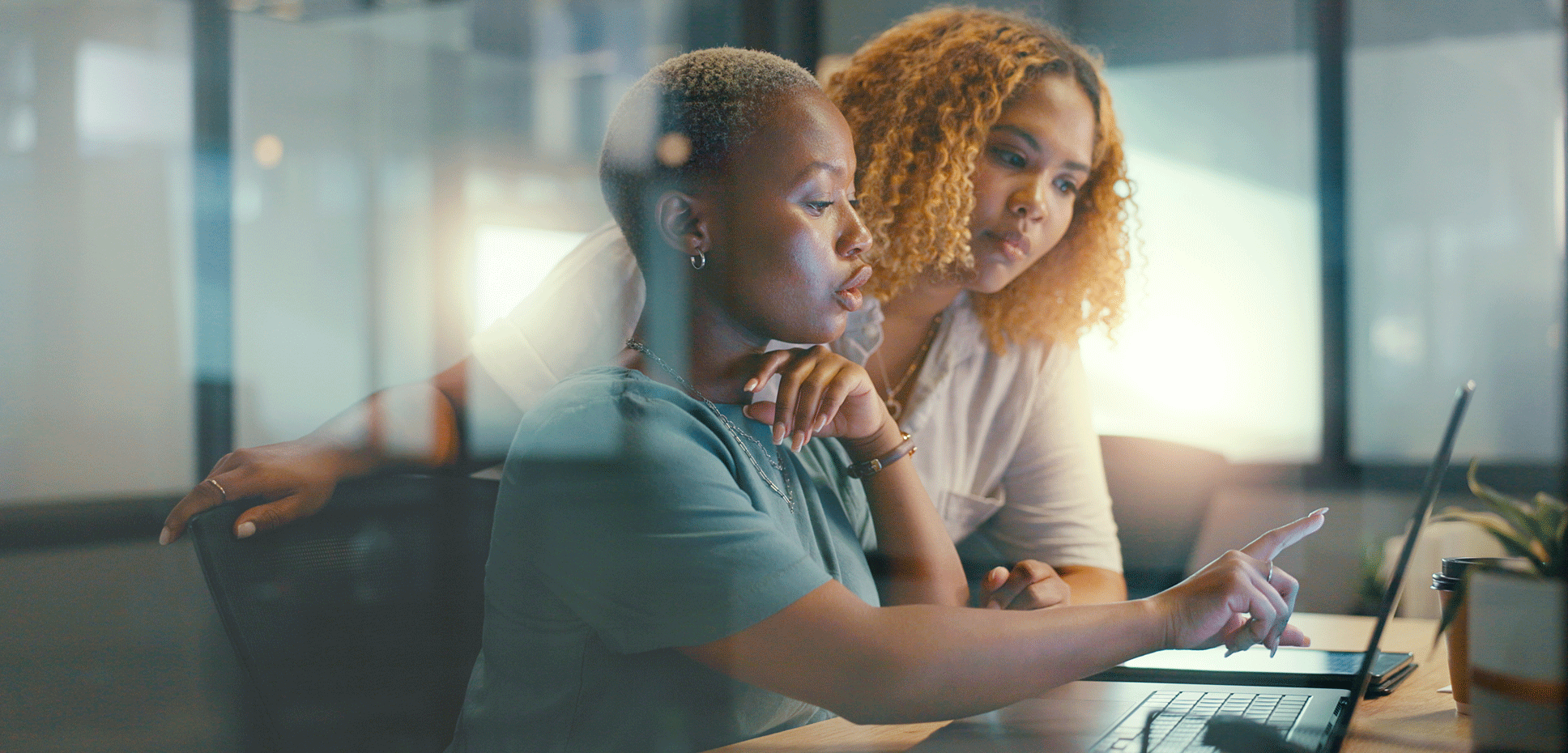 A pair of African American women review an analysis on a computer.