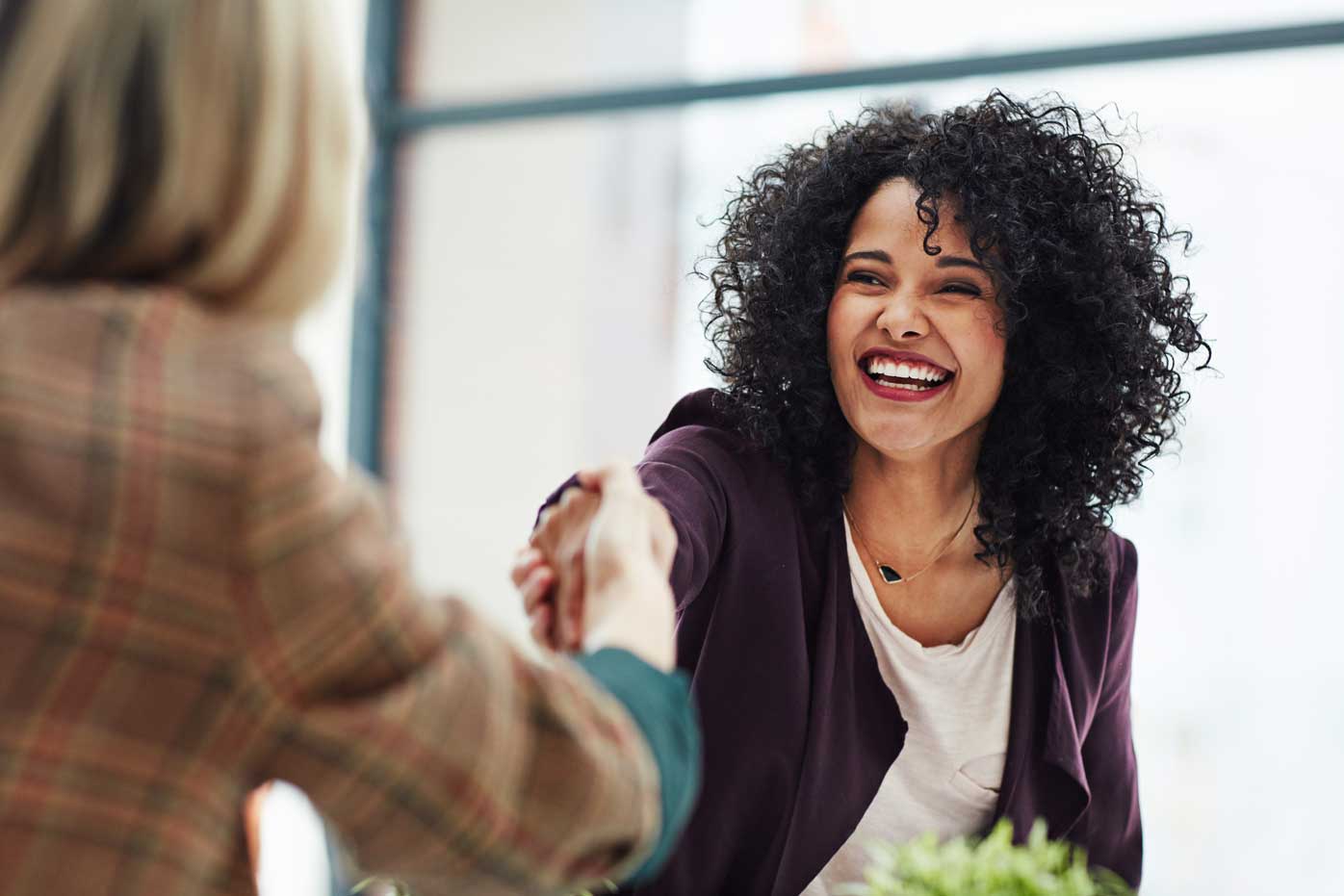 A friendly woman shakes hands with a colleague