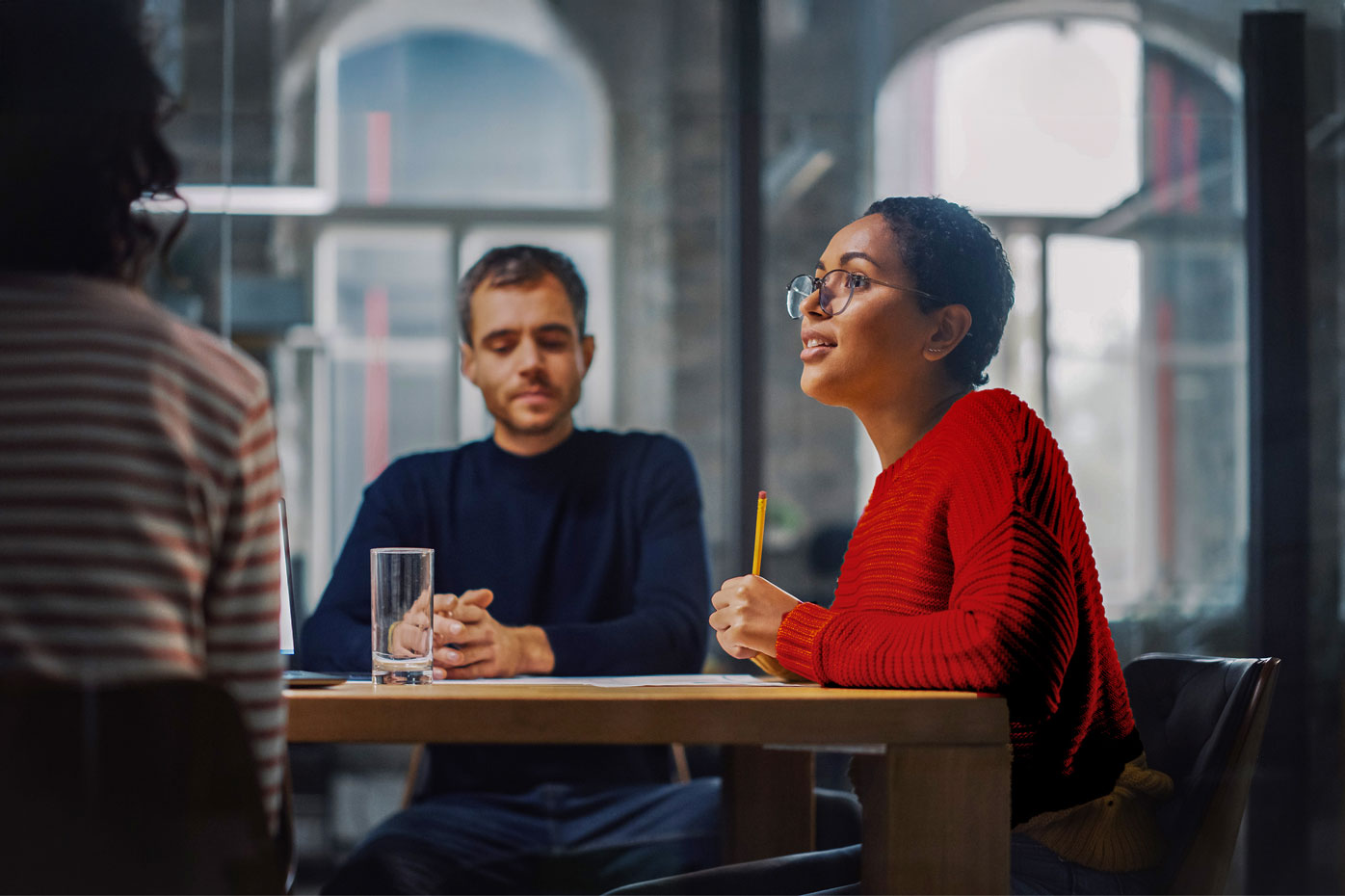 A woman in a red sweater sits at a table with her team