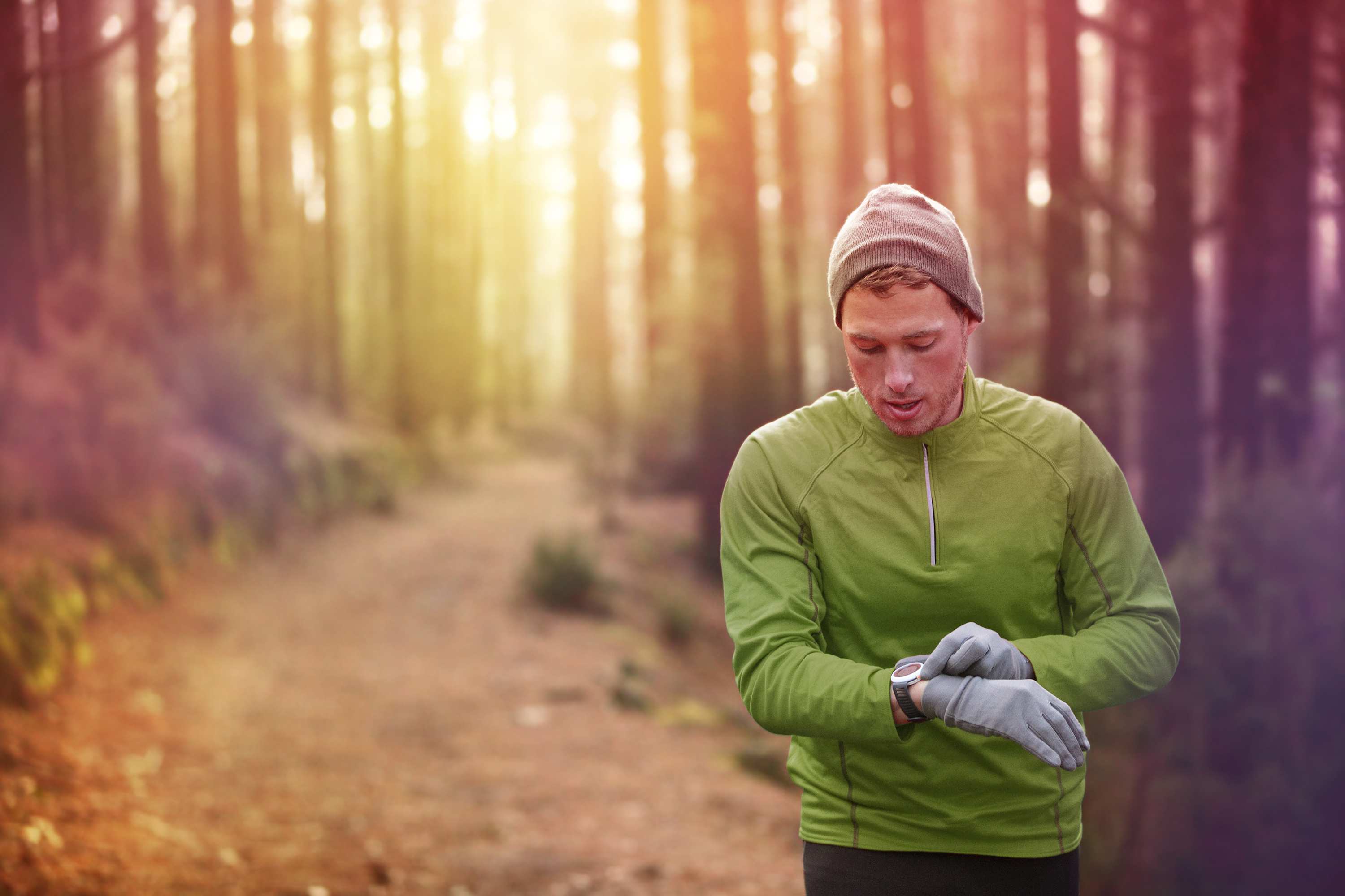 Runner in forest checking fitness tracker