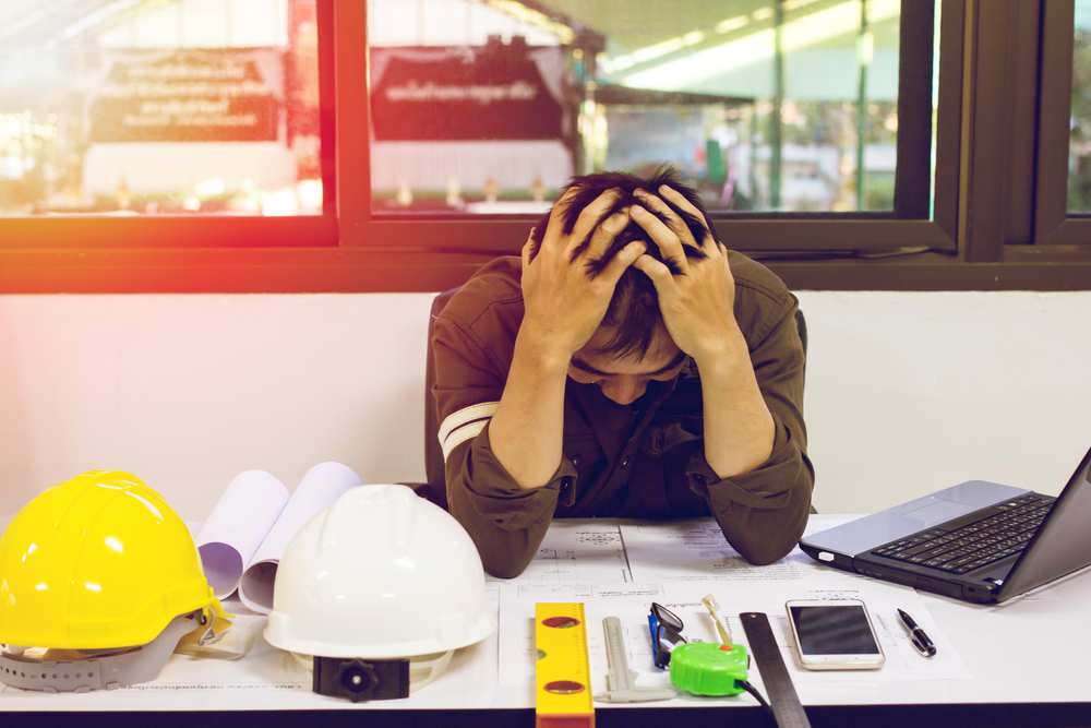 Work Related Disability: a worker on a worksite with head in hands