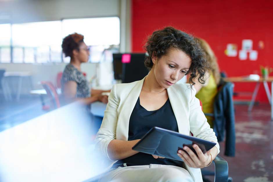 A woman intently studies an ipad, investigating medical research